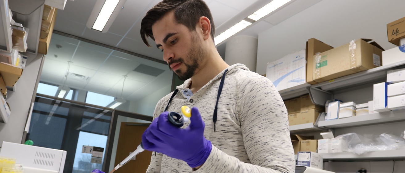A researcher wearing gloves and using a pipette
