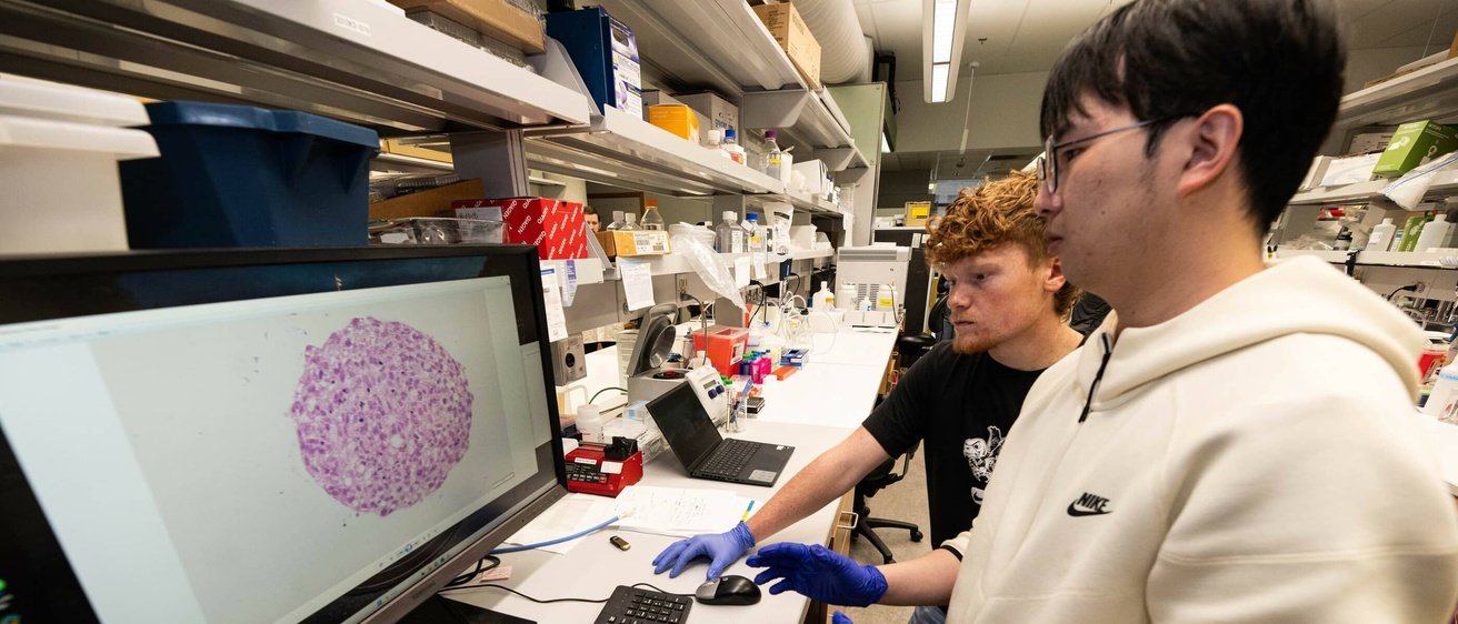 Two students look at a computer in the lab